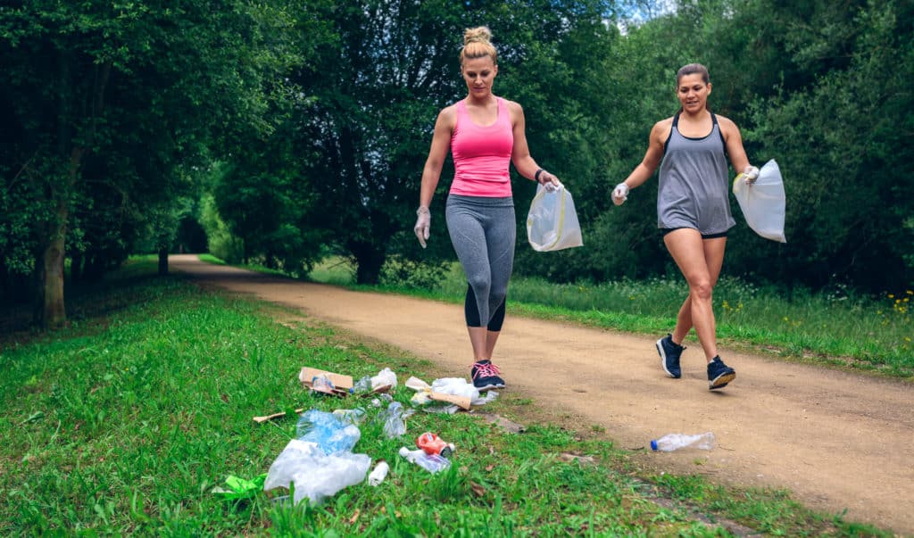 Twee vrouwen ruimen al lopend afval op.