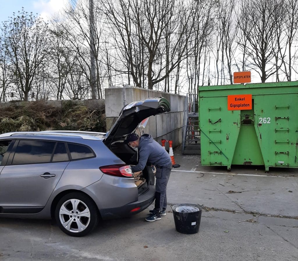 Een man ledigt zijn autokoffer met materialen voor in het recyclagepark.