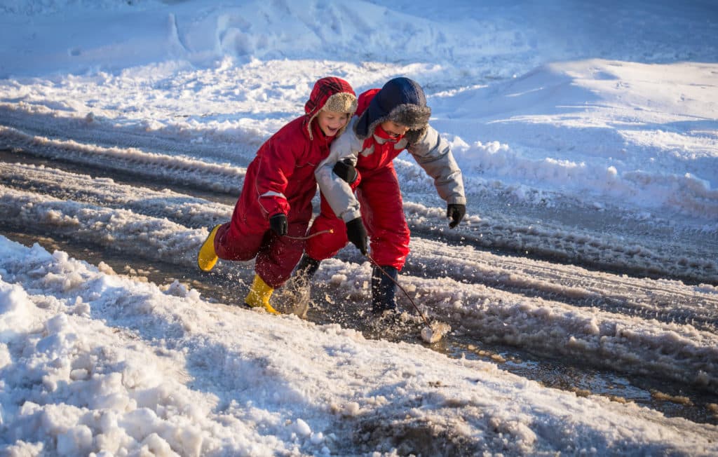 Twee kinderen spelen in een sneeuwstraat.