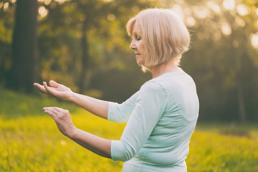 oudere dame die buiten yoga beoefent