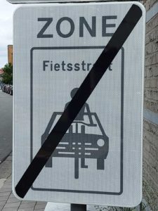Wit bord fietsstraat zone: einde van de zone: figuur van fietser voor een auto met een streep door