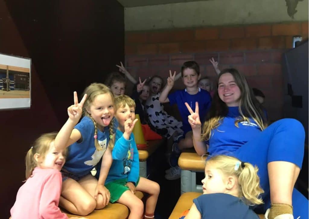 Jobstudent sportkamp poseert met verschillende kinderen.