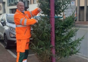 Medewerker van de technische dienst plaats een kerstboom in het straatbeeld.