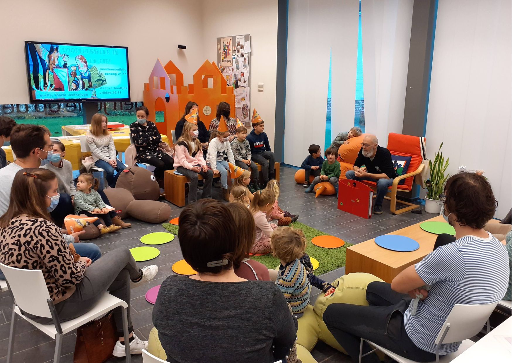 Voorleesmoment in de bib: verteller, kinderen en ouders in een cirkel.